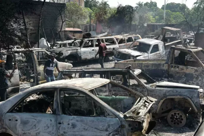 People look for salvageable pieces from burned cars at a mechanic shop that was set on fire during violence by armed gangs in Port-au-Prince, Haiti, Monday, March 25, 2024.